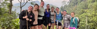 A group of students pose while on a hike in Guatemala; the forest is visible behind them