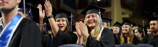 Two graduates cheer and clap during the University's Commencement ceremony
