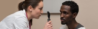 A Physician Assistant student practices using an ophthalmoscope on a patient's eyes