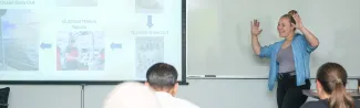 A UNE student presents a slideshow to a room of people