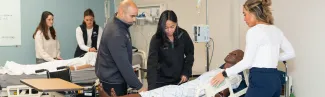 A group of D P T students practice working on a patient simulator in the Simulation Lab