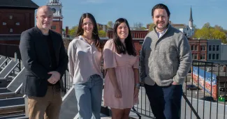 UNE business and Atlantic Hospitality leaders pose in front of the Biddeford skyline