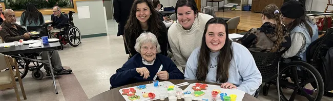Three female students pose with a resident of Portland's Barron Center, a long-term care facility