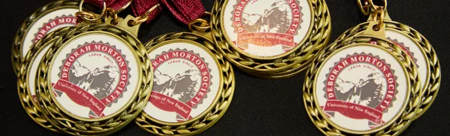 Several medals bearing the Deborah Morton Society seal are splayed out on a table