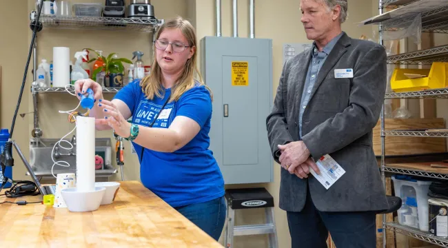A student displays a marine research device fashioned from PVC pipes