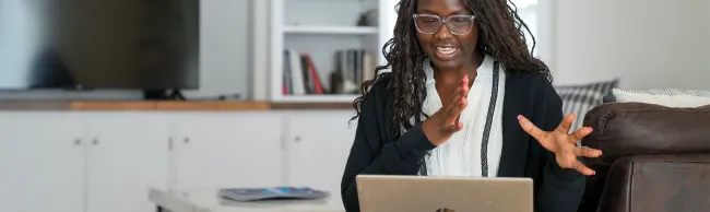 A U N E social work student gestures animatedly while attending an online class from home.