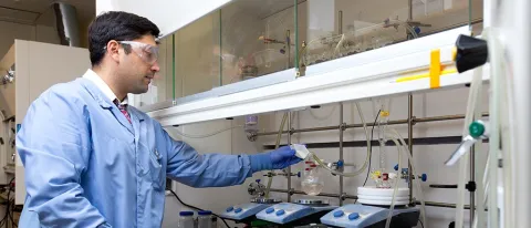 a pharmacy student wearing scrubs and safety goggles works in the lab