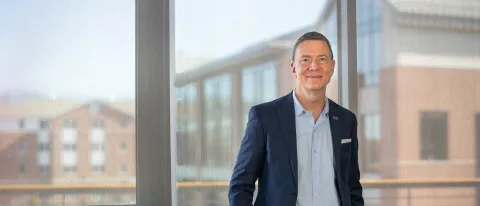 U N E President James Herbert poses in front of a window overlooking the Biddeford Campus