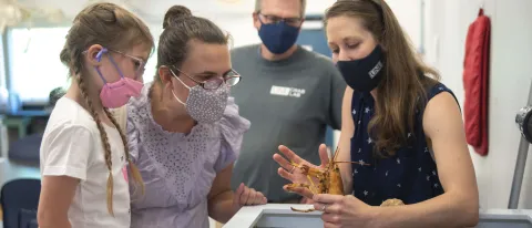 Girl and family meet yellow lobster in Marine Science Center