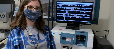 Woman stands in front of computer, phytoplankton displayed on screen