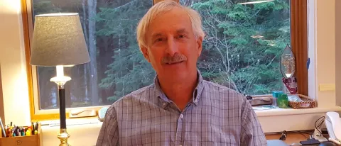 UNE professor Jake Plante stands and smiles at camera