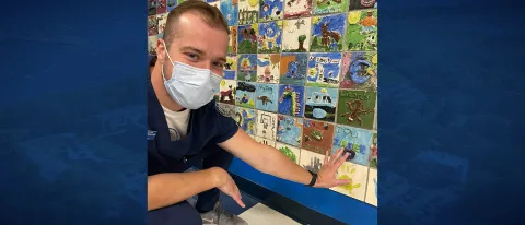 Male student touches wall art he made as a kid