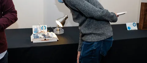 A person looks at a piece of art, which is a boat made of medical supplies