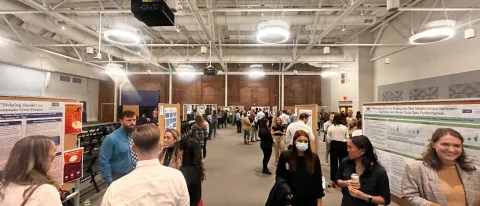 Physical therapy students present at their annual research symposium. Crowds gather to watch presentations