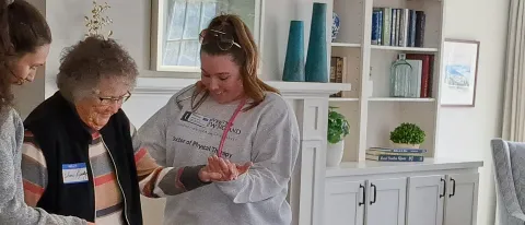 Physical therapy students assist an elderly woman during a routine health screening