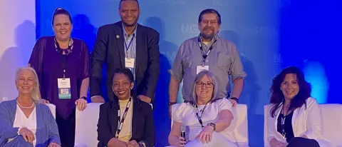 A group of men and women pose for a photo at a conference