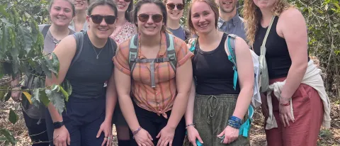 A group of students pose while on a hike in Guatemala; the forest is visible behind them