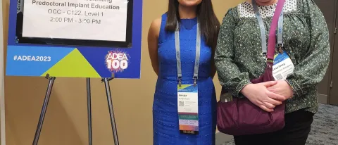 A student and faculty member pose in front of a research poster