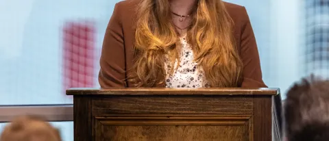A student speaks at a podium during the PSI CHI induction ceremony