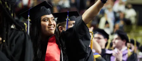 A student points to the crowd during the 187th Commencement ceremony at the Cross Insurance Arena in Portland