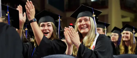 Two graduates cheer and clap during the University's Commencement ceremony 