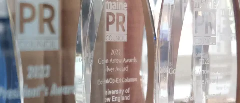Image of a Golden Arrow award with UNE's winning op-Ed listed