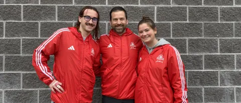 Aidan O'Keefe, Christopher Rizzo, and Riley Billings pose in front of a wall at the Boston Marathon