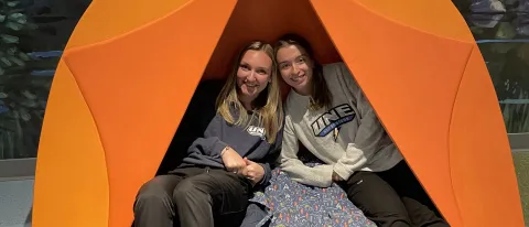 Two female students pose in an orange tent