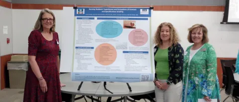 Three UNE faculty members stand next to a research poster