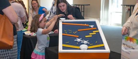 A child plays with an adaptive toy at a display table
