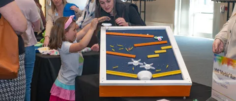 A child plays with an adaptive toy at a display table