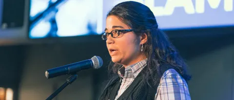 woman on stage speaking into mic