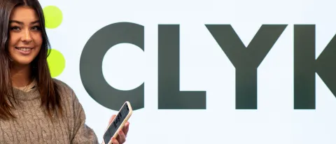 Abbie Anderson poses with a mobile phone. The name of her app, Clyk, is shown behind her