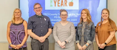 Five UNE alumni — Dawn McLaughlin, Joshua Chard, Lacey Todd, Katie Flannery, and Emily Rosser — are pictured against a whiteboard