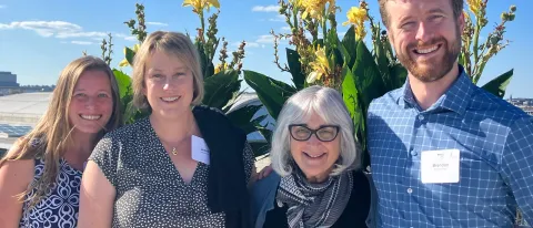 Four researchers pose in front of a flowers outside