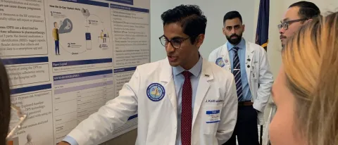 COM student Jenson Kaithamattam points to his research poster as he presents at the the COM research forum