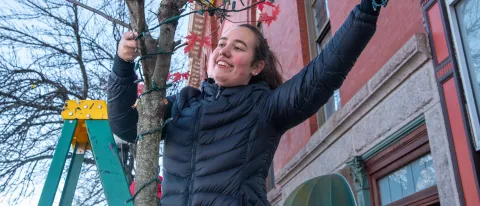 A student smiles as she hangs lights in front of Biddeford's City Theater