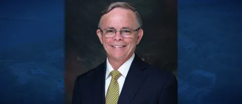 Portrait of James Tracy set against a blue background