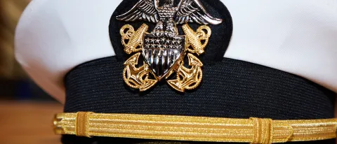 A military captain's hat with American flags in the background