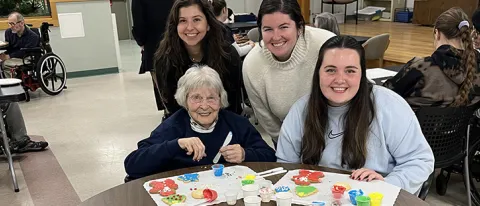 Three female students pose with a resident of Portland's Barron Center, a long-term care facility