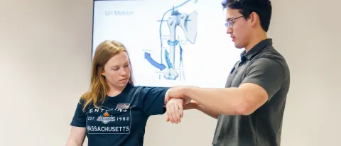 A P T student practices arm exercises on another student