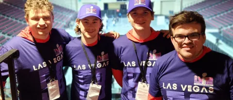 Four students pose wearing NFL-themed shirts