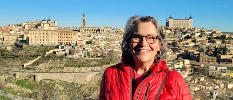 A woman smles for a photo in front of a countryside Spanish city 