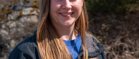 Portrait of a woman smiling in front of the forest