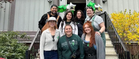 A group of UNE students poses in front of UNE's Ludcke Auditorium 