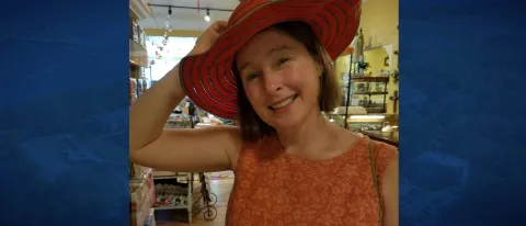 Susan McHugh poses wearing a red hat