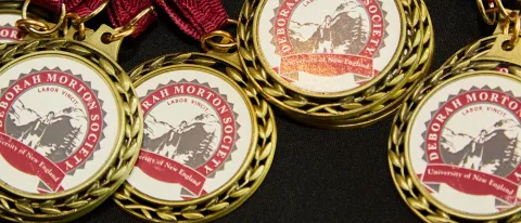Several medals bearing the Deborah Morton Society seal are splayed out on a table