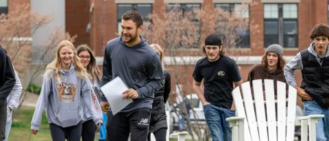 A UNE student leads a group of teenagers through field games