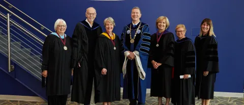 A group of people in regalia pose for a photo