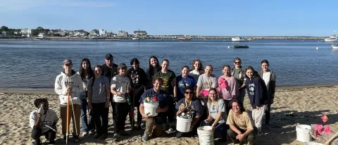 A group of students pose with buckets on Freddy Beach after cleaning up the sands